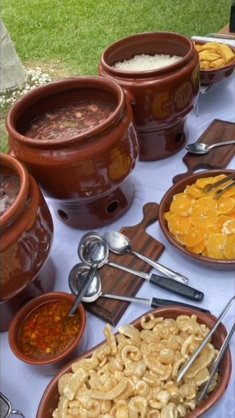 Feijoada servida em panelas de barro com acompanhamentos
