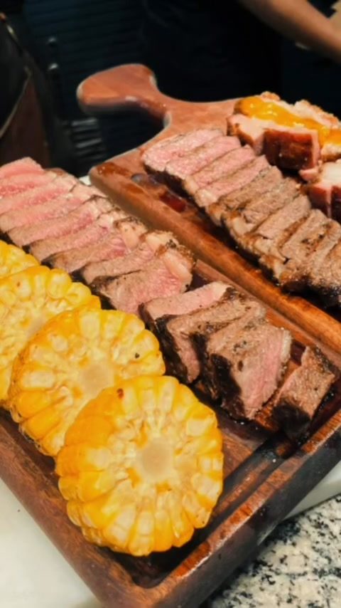 Tábua com cortes fatiados e milho na brasa